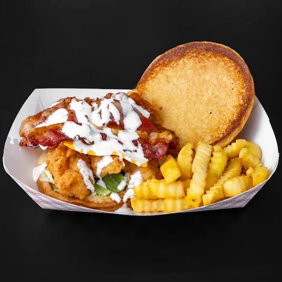 Jim Bob's Chicken Fingers sandwich with bacon, cheese, sauce, and crinkle-cut fries in a paper tray.