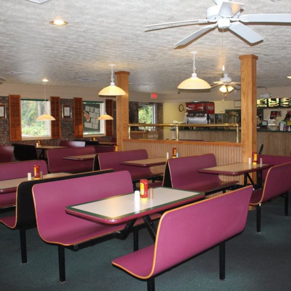 Interior of Jim Bob's Chicken Fingers, showing empty dining room with purple booths, tables, and ceiling fans.