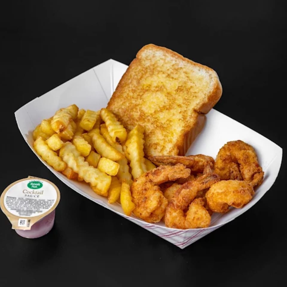 Jim Bob's fried shrimp, crinkle-cut fries, Texas toast, and cocktail sauce in a paper tray.